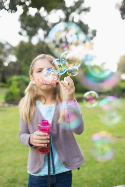 Ragazza che soffia bolle di sapone al parco