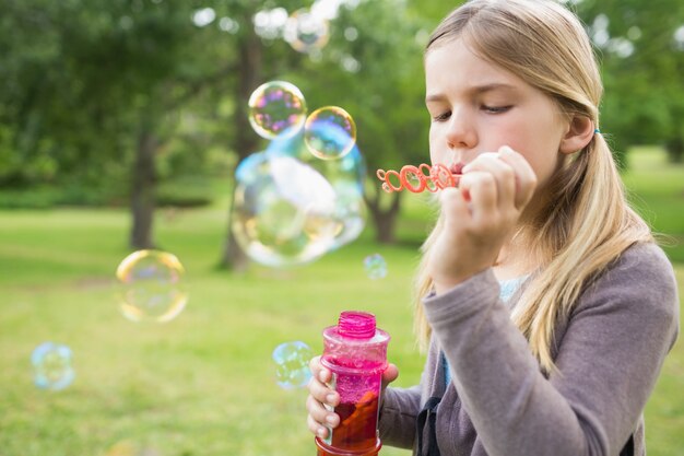 Ragazza che soffia bolle di sapone al parco