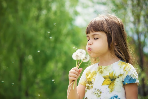 Ragazza che soffia i denti di leone in aria. messa a fuoco selettiva.