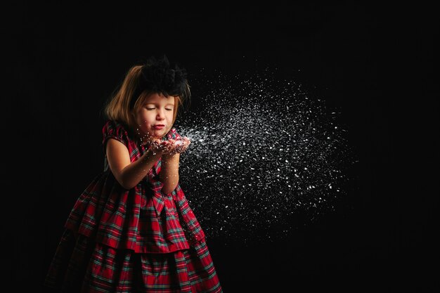 Ragazza che soffia la neve dalle sue mani