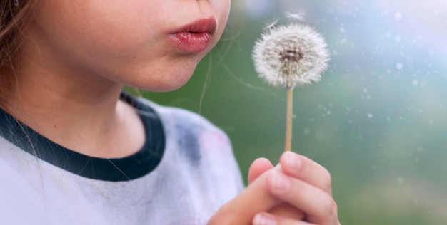 ragazza che soffia su un primo piano di dente di leone