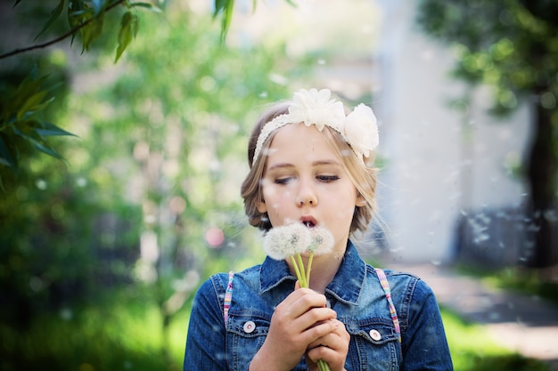 Ragazza che soffia un dente di leone all'aperto