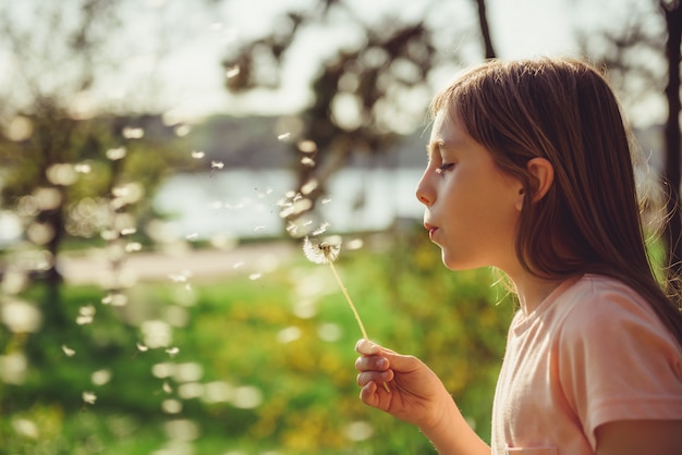 Ragazza che soffia un dente di leone