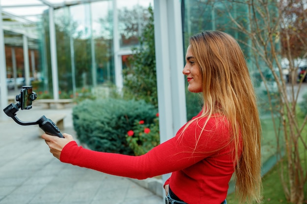 Ragazza che spara un video della rete sociale, vestiti rossi, concetto di stile di vita