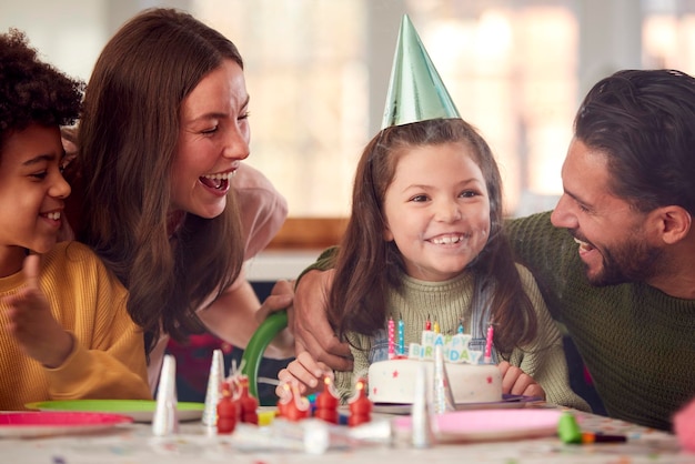 Ragazza che spegne le candeline sulla torta di compleanno alla festa con i genitori e gli amici a casa