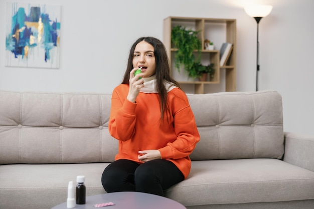 Ragazza che spruzza la medicina nella disinfezione orale nella sua prevenzione orale di infezioni respiratorie o Coronavirus COVID-19 protegge contro i batteri nella gola prima che il germe entri nei polmoni