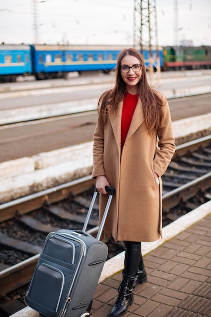 Ragazza che sta alla stazione ferroviaria, ritratto del turista in cappotto