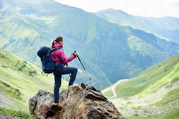 Ragazza che sta sopra la roccia e che gode delle montagne di vista