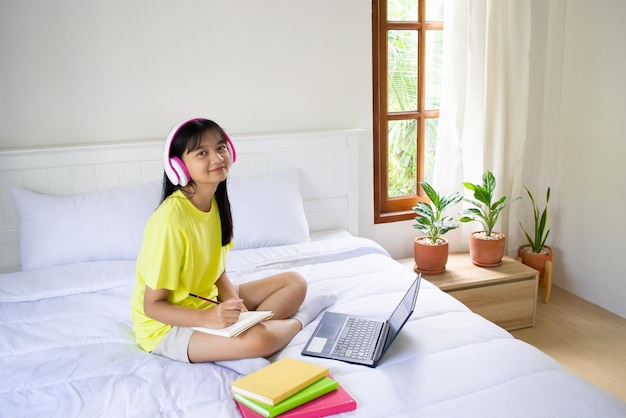 Ragazza che studia con il computer portatile sul letto in camera da letto