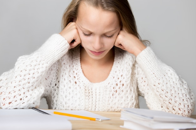 Ragazza che studia su un tavolo di legno