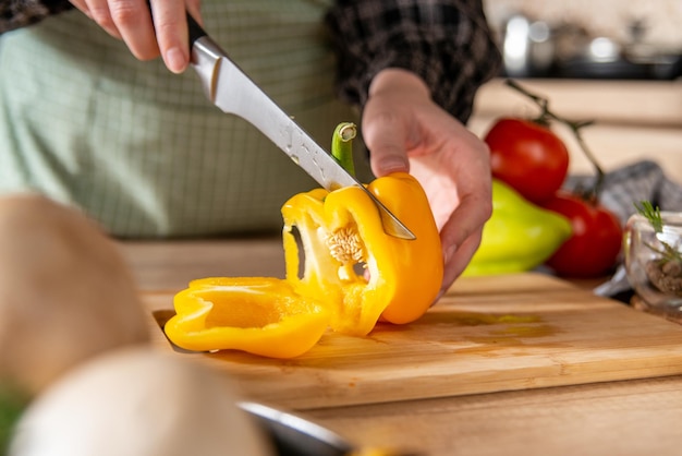 ragazza che taglia il peperone giallo, cucina casalinga, fondo della cucina