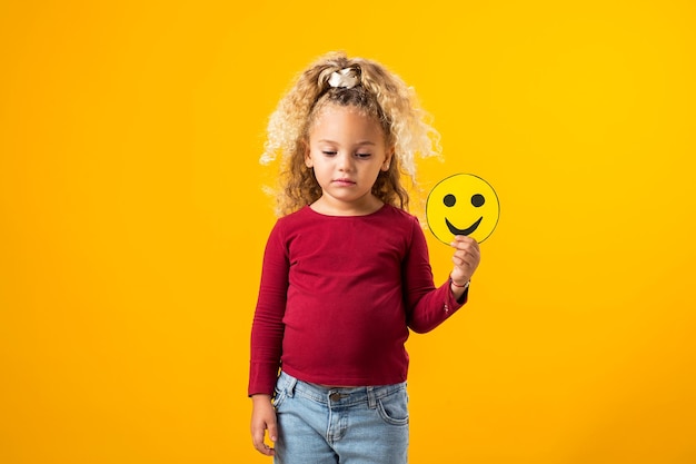 Ragazza che tiene emoticon tristi e felici Equilibrio emotivo dei bambini