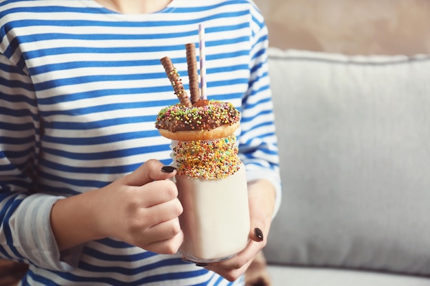 Ragazza che tiene frappè con ciambella e altri dolci in barattolo