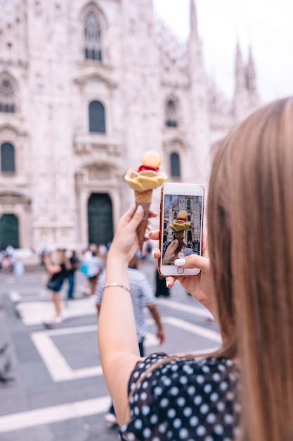 Ragazza che tiene il gelato e ne scatta delle foto sul backgrou