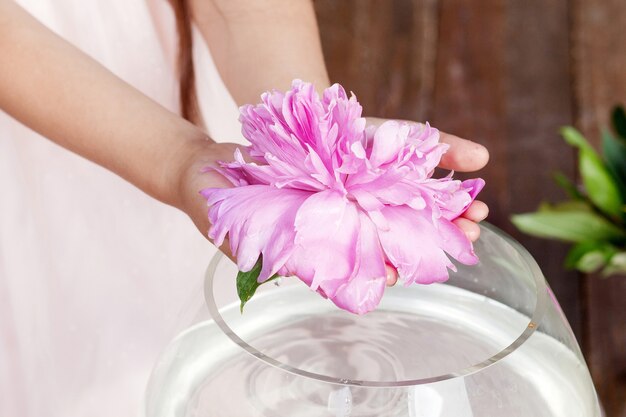 Ragazza che tiene in mano un fiore di peonia rosa. Chiudere l'immagine