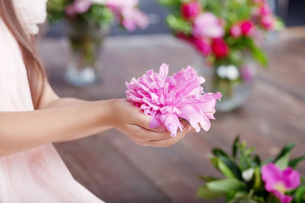 Ragazza che tiene in mano un fiore di peonia rosa. Chiudere l'immagine