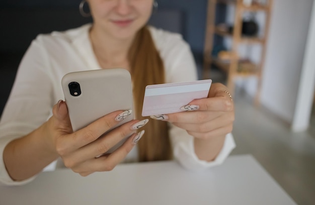 Ragazza che tiene in mano un telefono cellulare e una carta di credito