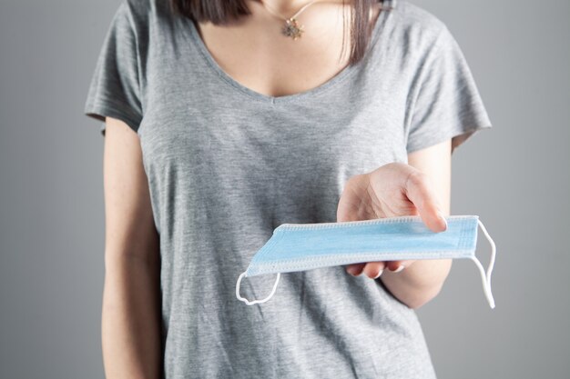 Ragazza che tiene in mano una maschera medica su un grigio