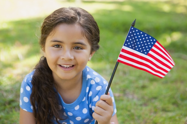 Ragazza che tiene la bandiera americana al parco