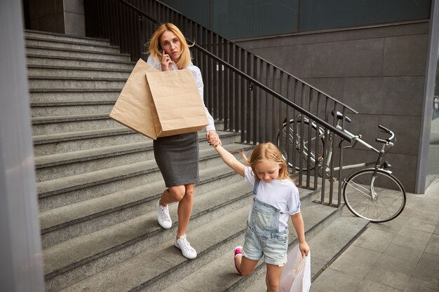 Ragazza che tiene la mano della madre mentre esce dal centro commerciale con un nuovo acquisto