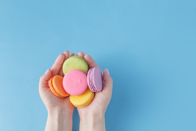 Ragazza che tiene macarons francesi colorati nelle mani