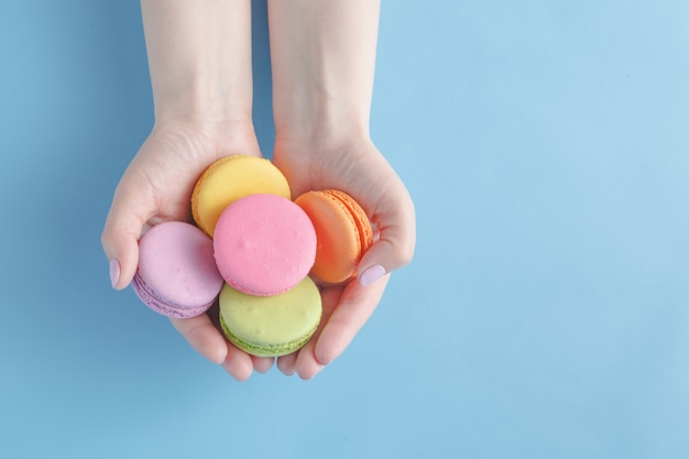 Ragazza che tiene macarons francesi colorati nelle mani