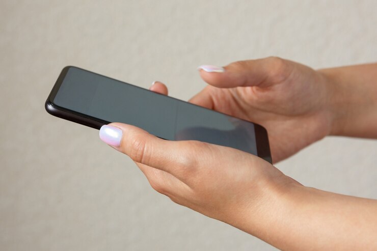 Ragazza che tiene smartphone in primo piano delle mani
