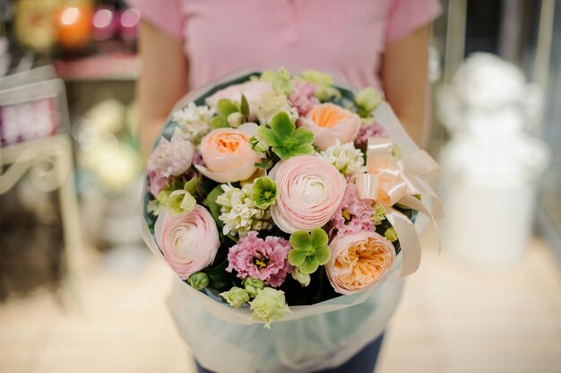 Ragazza che tiene un bellissimo mazzo di fiori teneri di colore verde e rosa