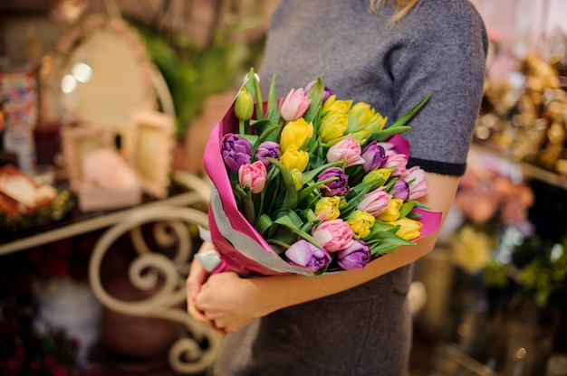 Ragazza che tiene un bellissimo mazzo di tulipani rosa, gialli e viola