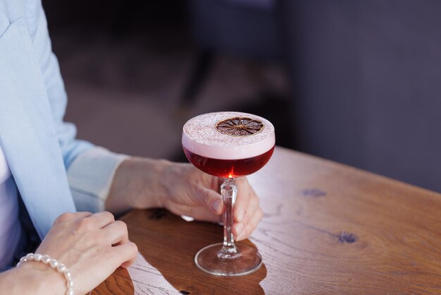 Ragazza che tiene un bicchiere con un cocktail in un concetto di ristorante primo piano bar o ristorante