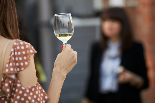 ragazza che tiene un bicchiere di vino bianco nelle sue mani a un primo piano di festa