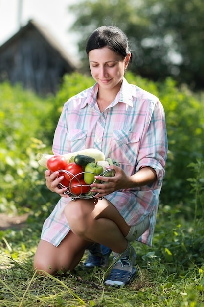 Ragazza che tiene un cesto di verdure raccolte in giardino