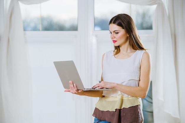 Ragazza che tiene un computer portatile al chiuso a casa