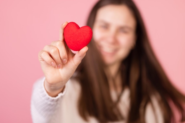 Ragazza che tiene un cuore nelle sue mani primo piano su sfondo rosa il concetto di san valentino