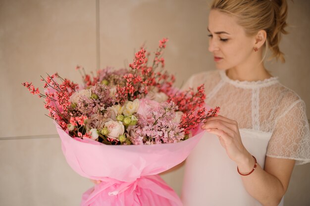 Ragazza che tiene un mazzo della molla di colore rosa tenero e dei fiori bianchi