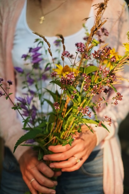 Ragazza che tiene un mazzo di fiori di campo in mano