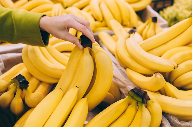 Ragazza che tiene un mucchio di banane al supermercato.