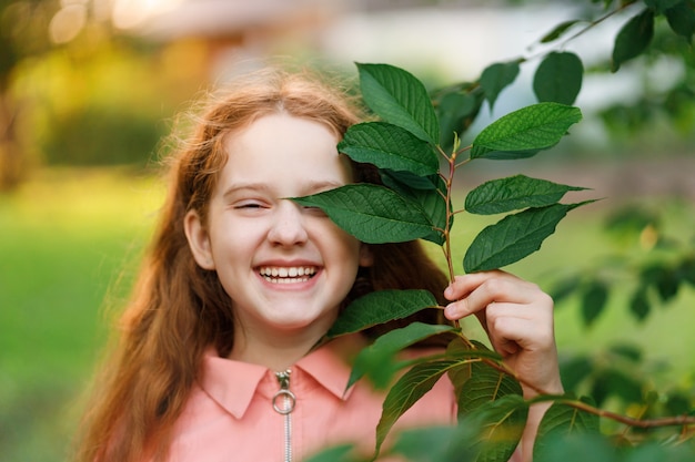 Ragazza che tiene un ramo con foglie verdi vicino al viso