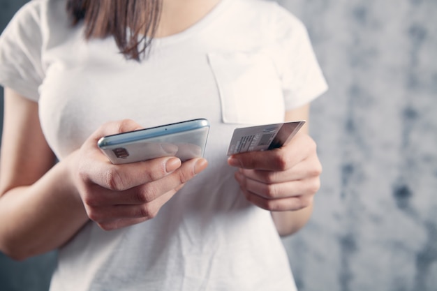 Ragazza che tiene un telefono e una carta di credito nelle sue mani