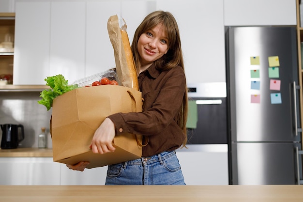 Ragazza che tiene una borsa della spesa con le verdure mentre è in piedi in cucina