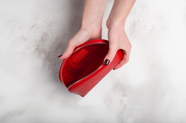 Ragazza che tiene una borsa rossa dell'annata nelle mani su bianco