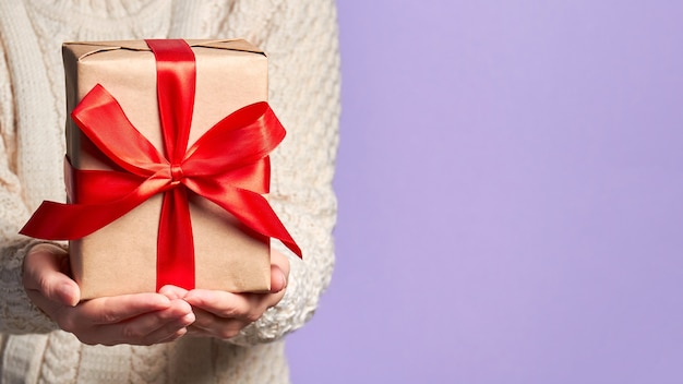 Ragazza che tiene una confezione regalo di Natale con un nastro rosso