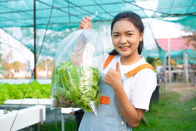 Ragazza che tiene una grande borsa di verdure alla fattoria idroponica