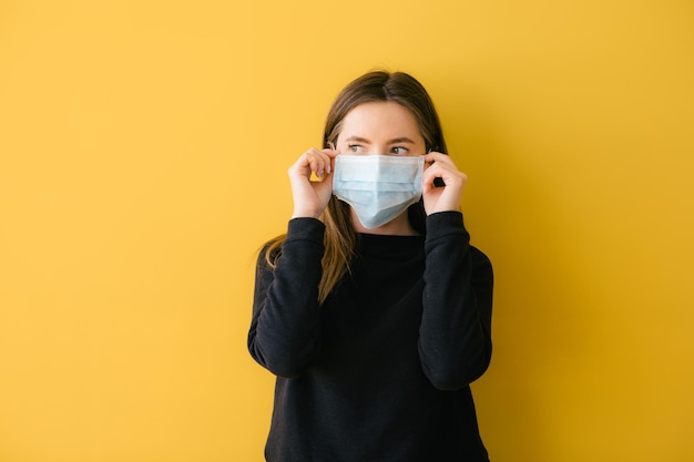 ragazza che tiene una maschera protettiva su sfondo giallo