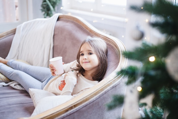 Ragazza che tiene una tazza a casa a Natale