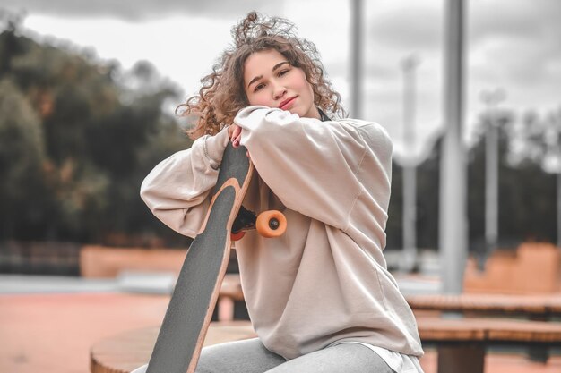 Ragazza che tocca lo skateboard seduto nel parco