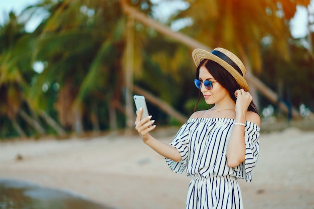 ragazza che utilizza un cellulare mentre si sveglia lungo la spiaggia