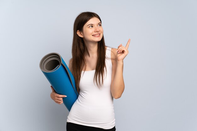 Ragazza che va a lezioni di yoga tenendo un tappetino rivolto verso l'alto una grande idea