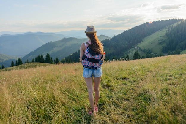 ragazza che viaggia con uno zaino in montagna