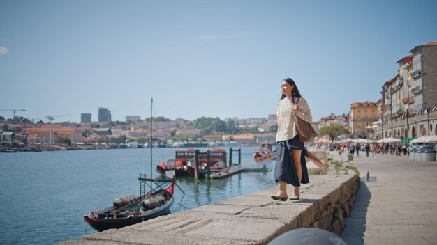 Ragazza che viaggia sul fiume paesaggio cittadino passeggiando con la borsa da sola turista signora che cammina